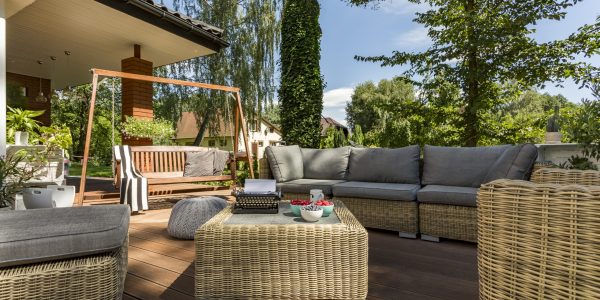 Cozy terrace with wicker furniture and wooden garden swing